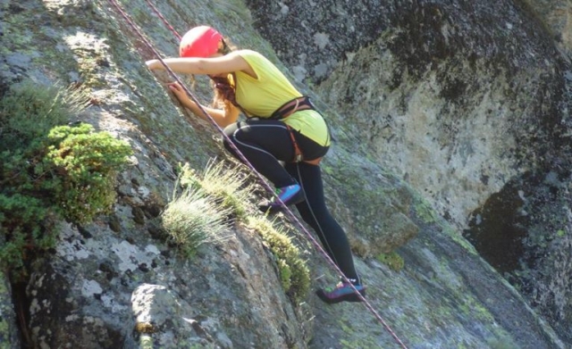 chica practicando escalada en una roca natural
